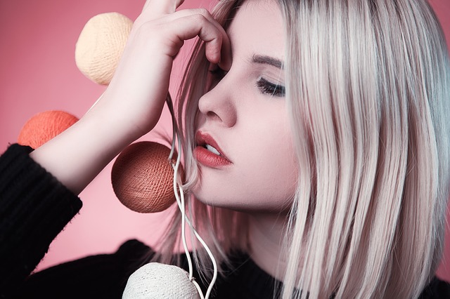 Blondýna si pri tvári drží pletené gule.jpg